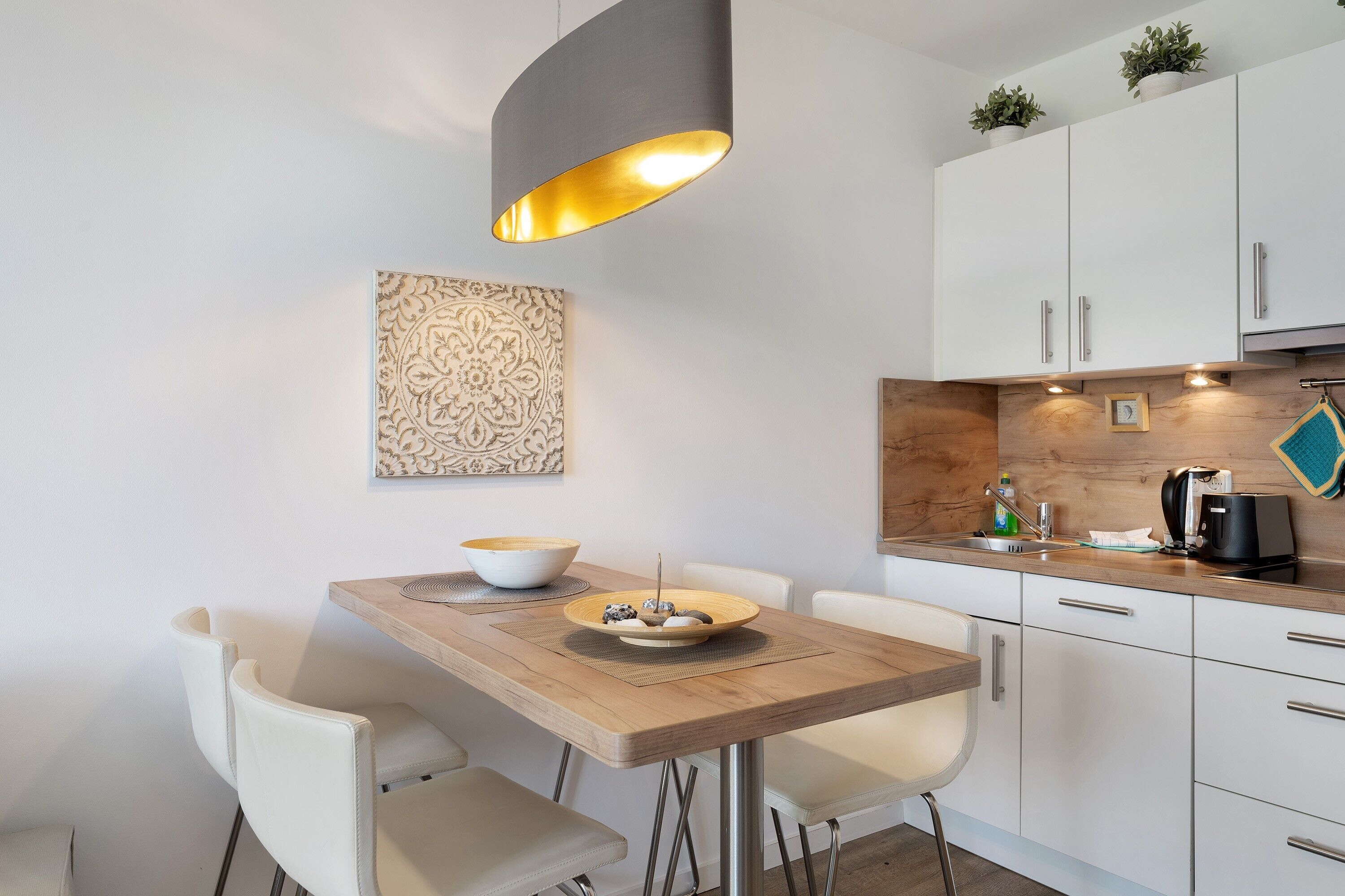 Eine moderne Küche mit weißen Schränken, einer Holz Arbeitsplatte und einer Pendelleuchte.