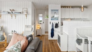 Ein modernes, weißes Wohnzimmer mit Holzboden, einem grauen Sofa und einem kleinen Tisch mit Lampe.