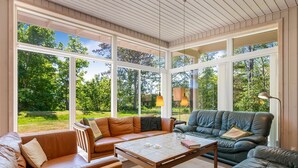 A sunroom with large windows, leather sofas, a coffee table, and a lamp. - "Dagny" - 100m from the sea by Interhome (Knebel)