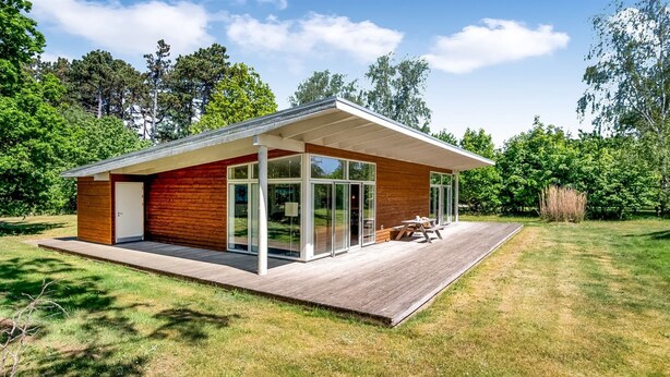 A modern house with a wooden deck, large glass windows, and a covered patio area. - "Dagny" - 100m from the sea by Interhome (Knebel)