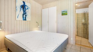 A bedroom with a bed, a painting, a wardrobe, and a shower area. - "Dagny" - 100m from the sea by Interhome (Knebel)