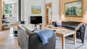 En moderne stue med pejs, fjernsyn, sofa og et billede på væggen.