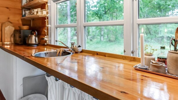 Een houten keuken in een chalet, met een groot raam, een spoelbak en diverse keukenbenodigdheden op het aanrecht.