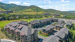 A residential complex with multiple apartment buildings, a central courtyard, and a mountainous backdrop.
