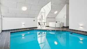 A modern indoor swimming pool with clear blue water, a seating area with chairs, and a spa tub. - "Ardan" - 450m from the sea by Interhome (Ebeltoft)