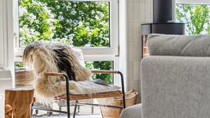 A cozy living room with a wicker chair, a grey sofa, and a large window with a view of greenery. - "Hermund" - 100m from the sea by Interhome (Ebeltoft)