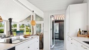 A modern kitchen with white cabinetry, a large island, and a built-in stove. - "Hermund" - 100m from the sea by Interhome (Ebeltoft)