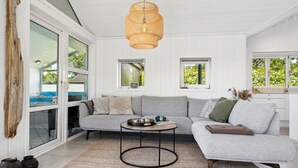 A modern living room with a grey sectional sofa, a round coffee table, and a woven pendant light. - "Hermund" - 100m from the sea by Interhome (Ebeltoft)