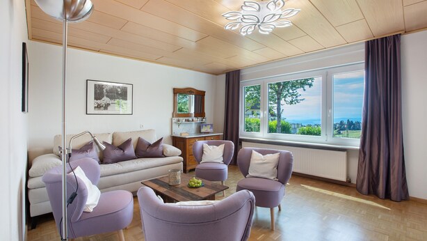 Una sala de estar moderna con sofá, sillones, una mesita de centro y vistas al exterior.