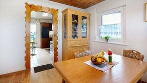 Un comedor con una mesa de madera, sillas, un aparador con puertas de vidrio y una ventana con vistas.