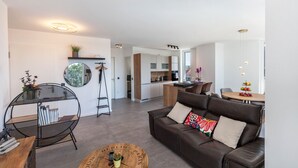 A modern living room with a leather sofa, a round coffee table, a black metal bookshelf, and a round mirror on the wall. - Apartment 'Yiwoo Home' with Private Terrace, Balcony and Wi-Fi (Gießen)