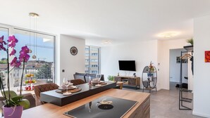 A modern living room with a large window, a flat-screen TV, a dining area, and a kitchen area. - Apartment 'Yiwoo Home' with Private Terrace, Balcony and Wi-Fi (Gießen)