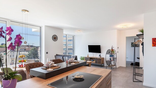 A modern living room with a large window, a flat-screen TV, a dining area, and a kitchen area. - Apartment 'Yiwoo Home' with Private Terrace, Balcony and Wi-Fi (Gießen)
