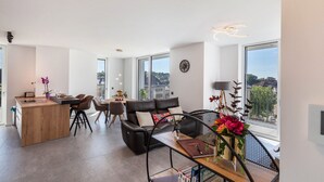 A modern living space with a dining area, a sofa, and a large window offering a view. - Apartment 'Yiwoo Home' with Private Terrace, Balcony and Wi-Fi (Gießen)
