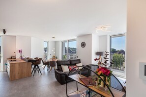 Un espace de vie moderne comprenant un coin repas, un canapé et une grande fenêtre donnant sur un paysage agréable.