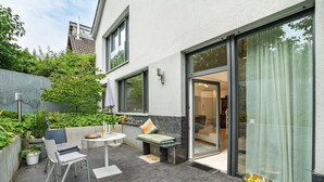 Une terrasse extérieure moderne, aménagée avec une table à manger, des chaises et un banc.