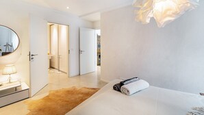 Une chambre à coucher moderne avec un grand lit, une lampe de chevet, un miroir et un luminaire suspendu.