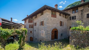 A stone building with multiple windows and a central entrance. - La Madonnina Apartment for 2 in Tenno (Tenno)