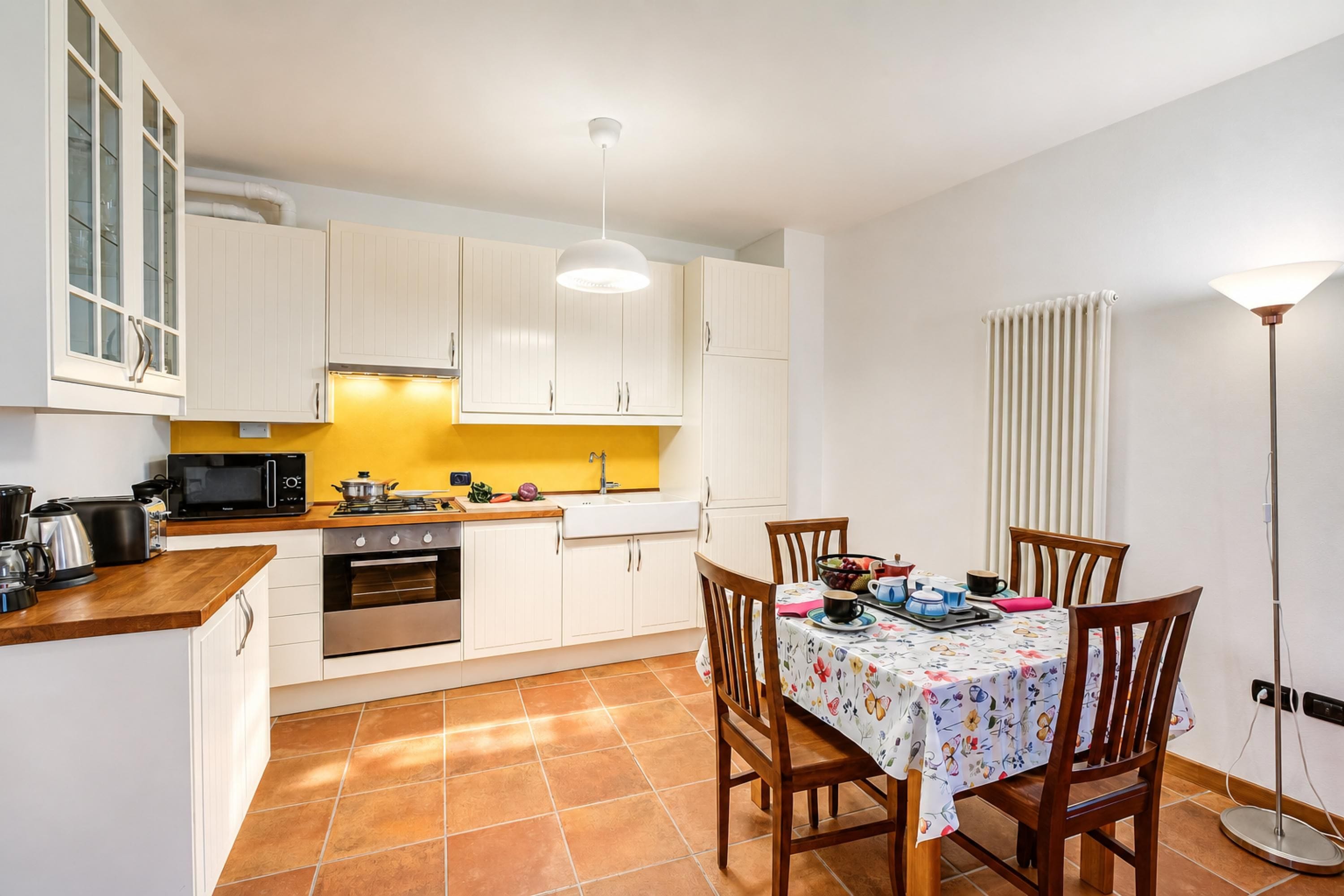 Cocina compacta con armarios blancos, microondas, estufa y una mesa de comedor con sillas.