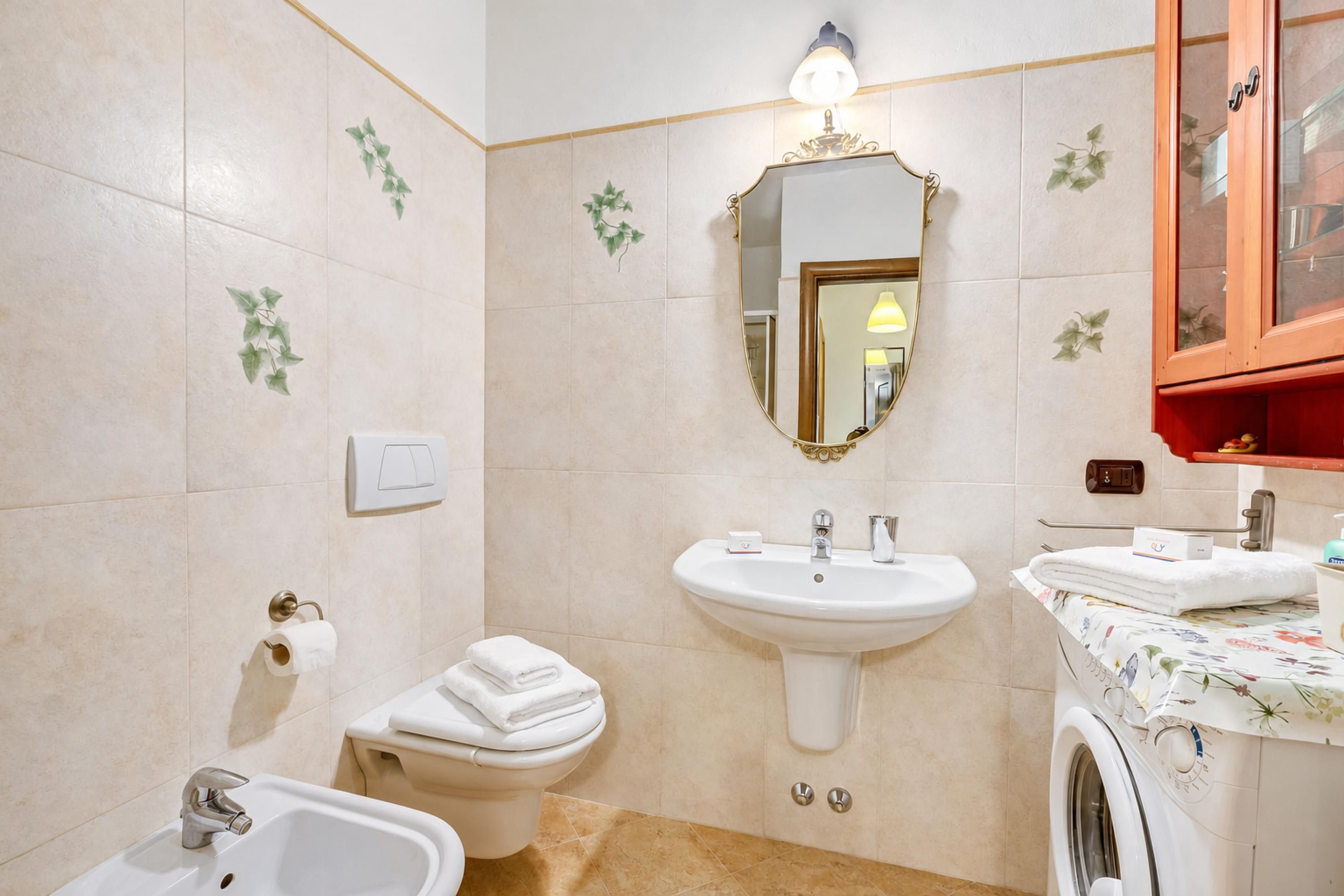 Un bagno con lavandino, WC, bidet e lavatrice.