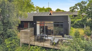 A modern house with a deck, large windows, and a chimney.