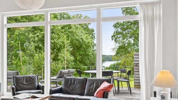 A modern living room with a large window, a sofa, and a table with chairs.