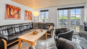 A modern living room with a leather sofa, a wooden coffee table, and two paintings on the wall. - "Birette" - 1.2km from the sea by Interhome (Ulfborg)