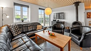 A modern living room with a leather sofa, a wooden coffee table, and a stone fireplace. - "Birette" - 1.2km from the sea by Interhome (Ulfborg)
