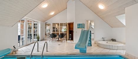 A swimming pool with a slide, a sun terrace, and a sauna area.