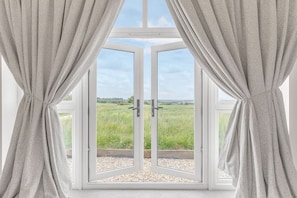Enjoy a serene view of the surrounding grassy field from the large window.