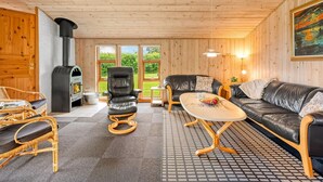 A cozy living room with a fireplace, leather sofas, a wicker chair, and a patterned floor. - "Åsa" - 500m to the fjord by Interhome (Tarm)