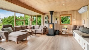 Ein gemütliches Blockhaus-Interieur mit einer großen Holzbalkendecke, einem Kamin aus Stein und einer Sofagarnitur.