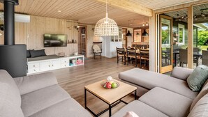 Ein modernes Wohnzimmer mit einer großen Couch, einem Couchtisch mit Obst, einem Fernseher und einem Kamin.