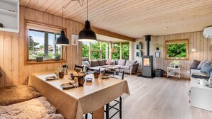 Ein gemütliches Blockhaus-Interieur mit Essbereich, einer Couch und einem Kamin.