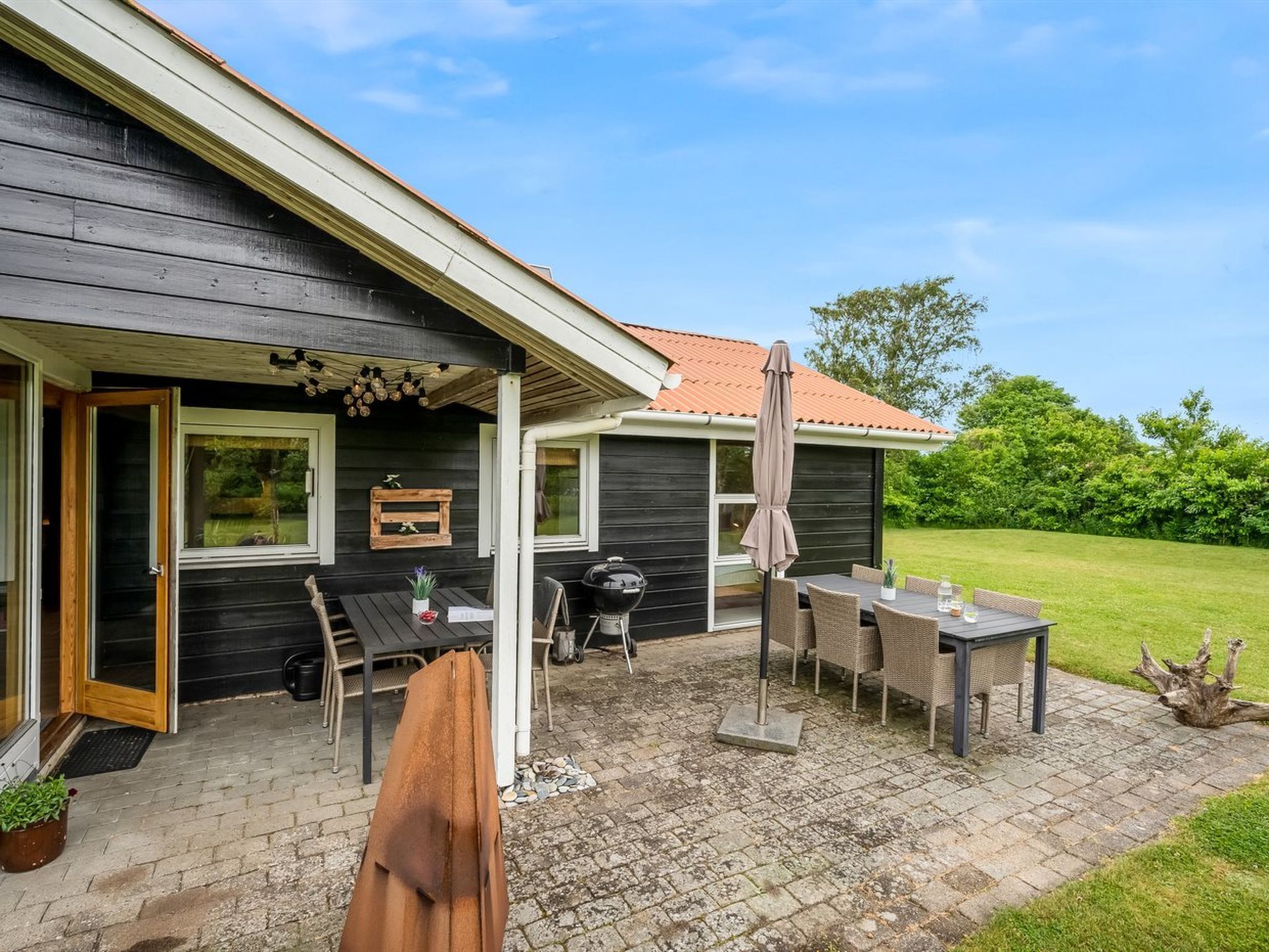 A patio with a table and chairs, a grill, and a wooden fence.