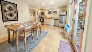 Une cuisine moderne dotée de meubles en bois, d’appareils électroménagers en acier inoxydable et d’un coin repas avec une table et des chaises en bois.