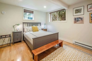 A bedroom with a bed, bedside tables, a bench, a window, and wall-mounted artwork. - #StayinMyDistrict Alberta Arts Daylight Studio (Portland)