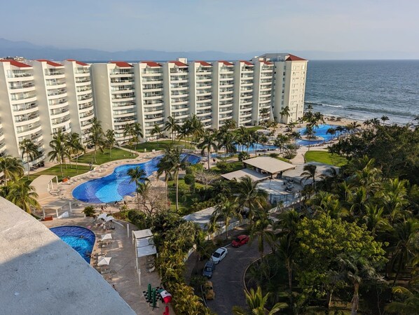 Un resort con varias piscinas, palmeras y vistas al océano.