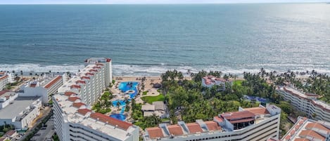 Un complexe hôtelier comprenant plusieurs bâtiments, un espace piscine et offrant une vue sur la plage.