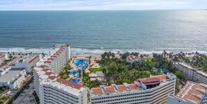 A resort with multiple buildings, a pool area, and a beach view.