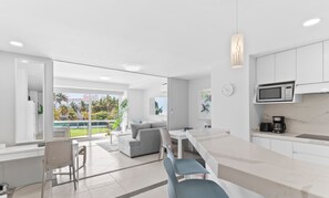 A modern kitchen with white cabinetry, a microwave, and a coffee maker.