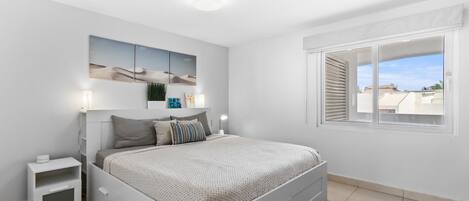 Una camera da letto moderna con un letto grande, comodini, un tavolino di fianco al letto e una lampada a soffitto.