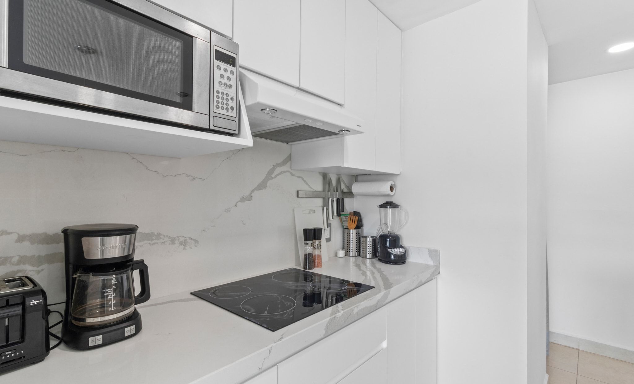 A modern kitchen with a built-in microwave, coffee maker, and induction cooktop.