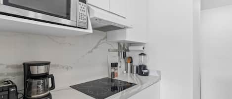A modern kitchen with a built-in microwave, coffee maker, and induction cooktop.