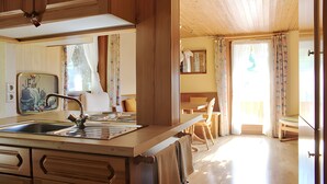 Une cuisine avec des meubles de rangement en bois, un évier et un coin repas comprenant une table et des chaises.