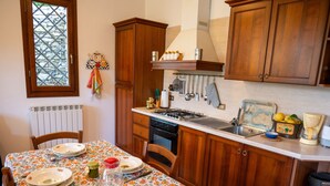 Une cuisine avec des meubles de rangement en bois, une cuisinière et une table à manger dressée avec des assiettes et des couverts.