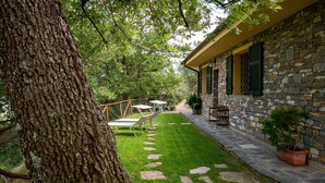 Un bâtiment en pierre avec un chemin en pierre menant à un espace extérieur aménagé pour s’asseoir.