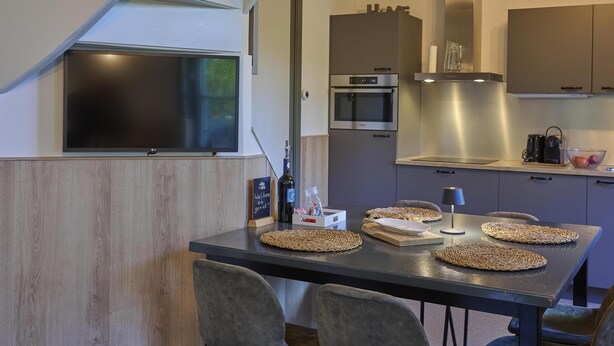 A modern kitchen with a built-in oven, microwave, and a flat-screen TV mounted on the wall. - Cosy house in wooded surroundings (Erp)