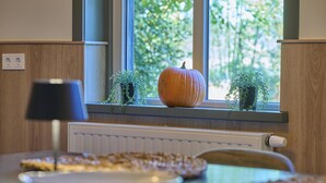 A kitchen with a window sill holding a pumpkin and two small potted plants. - Cosy house in wooded surroundings (Erp)
