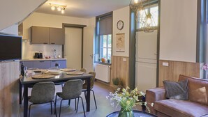 A modern living room with a dining area, a sofa, a coffee table, and a vase with flowers. - Cosy house in wooded surroundings (Erp)